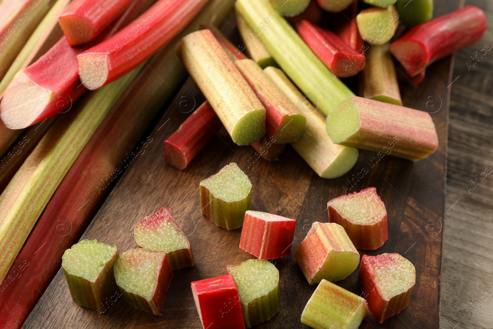 Photo of Many cut rhubarb stalks on wooden table, closeup