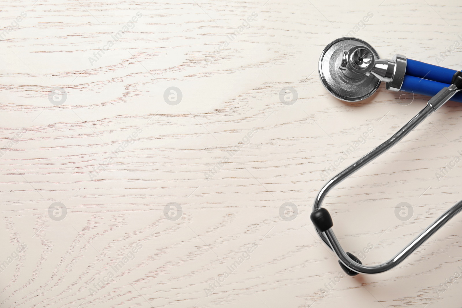 Photo of Stethoscope on wooden background, top view with space for text. Cardiology concept