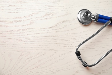 Stethoscope on wooden background, top view with space for text. Cardiology concept