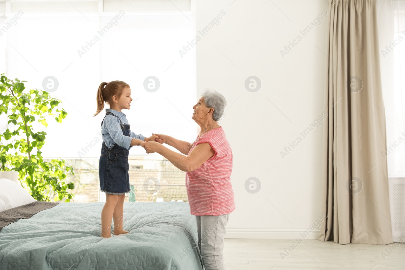 Photo of Cute girl and her grandmother playing together at home