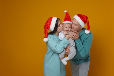 Photo of Happy couple with cute baby wearing Santa hats on yellow background, space for text. Christmas season
