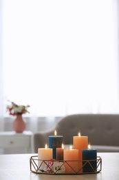 Photo of Tray with burning candles and flowers on table in living room. Space for text
