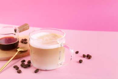 Cup of fresh coffee and beans on pink table. Space for text