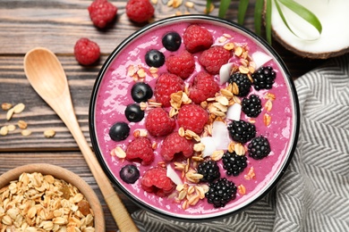 Photo of Delicious acai smoothie with fruits served on wooden table, flat lay