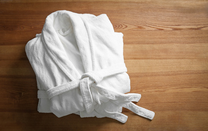 Photo of Clean folded bathrobes on wooden background, top view