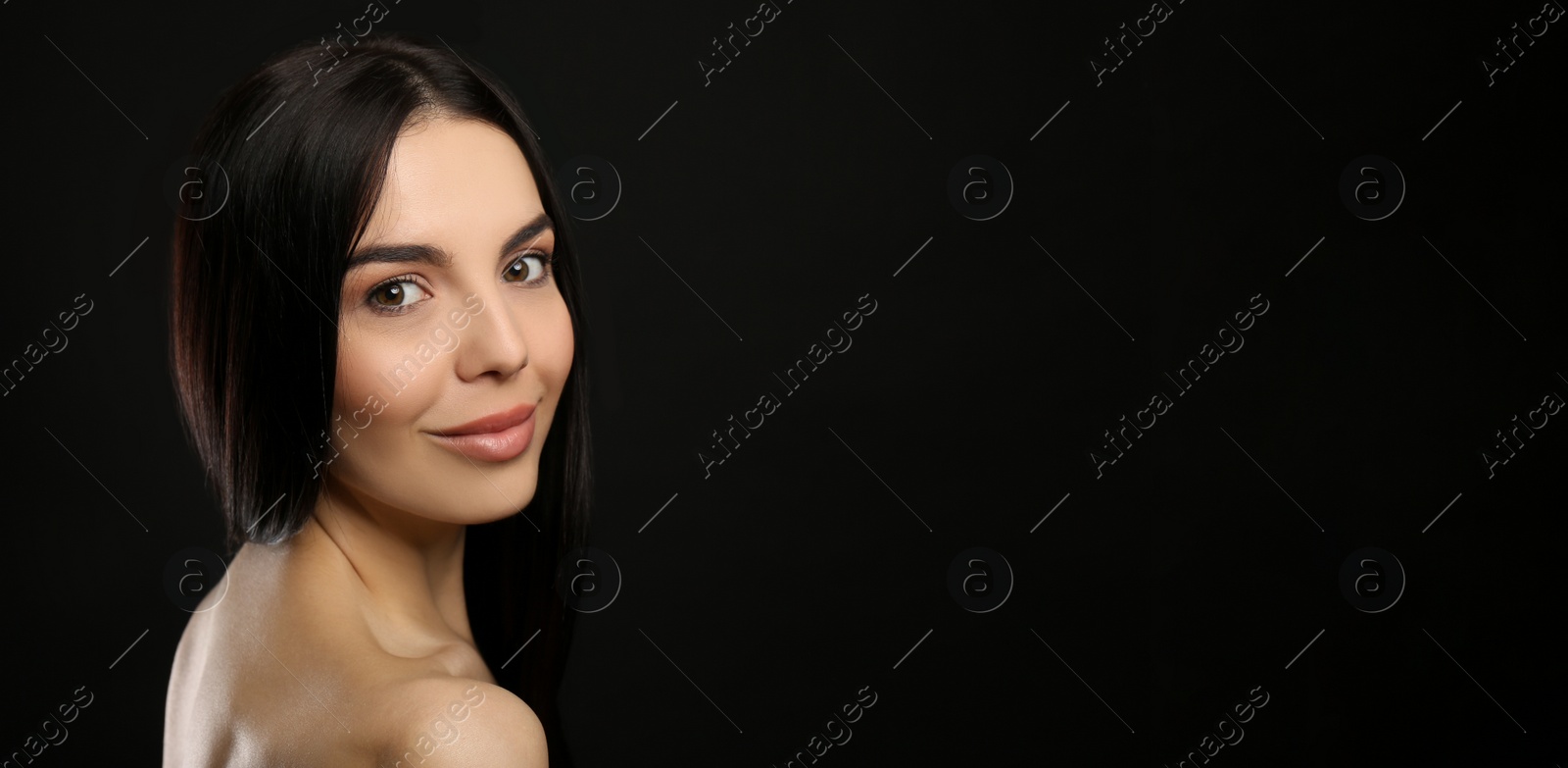 Photo of Portrait of happy young woman with beautiful black hair and charming smile on dark background, space for text