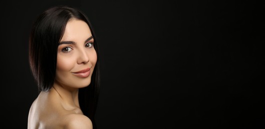 Photo of Portrait of happy young woman with beautiful black hair and charming smile on dark background, space for text
