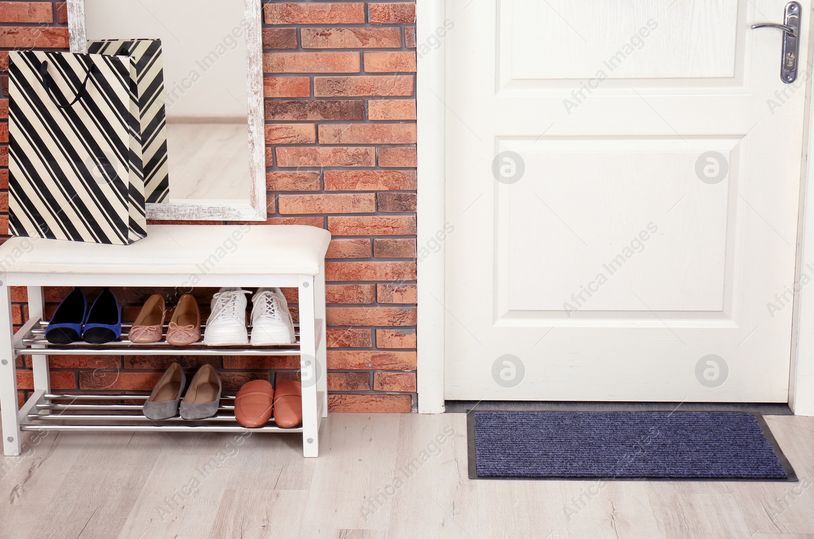 Photo of Hallway interior with shoe rack, mirror and mat near door