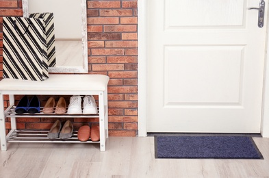 Hallway interior with shoe rack, mirror and mat near door