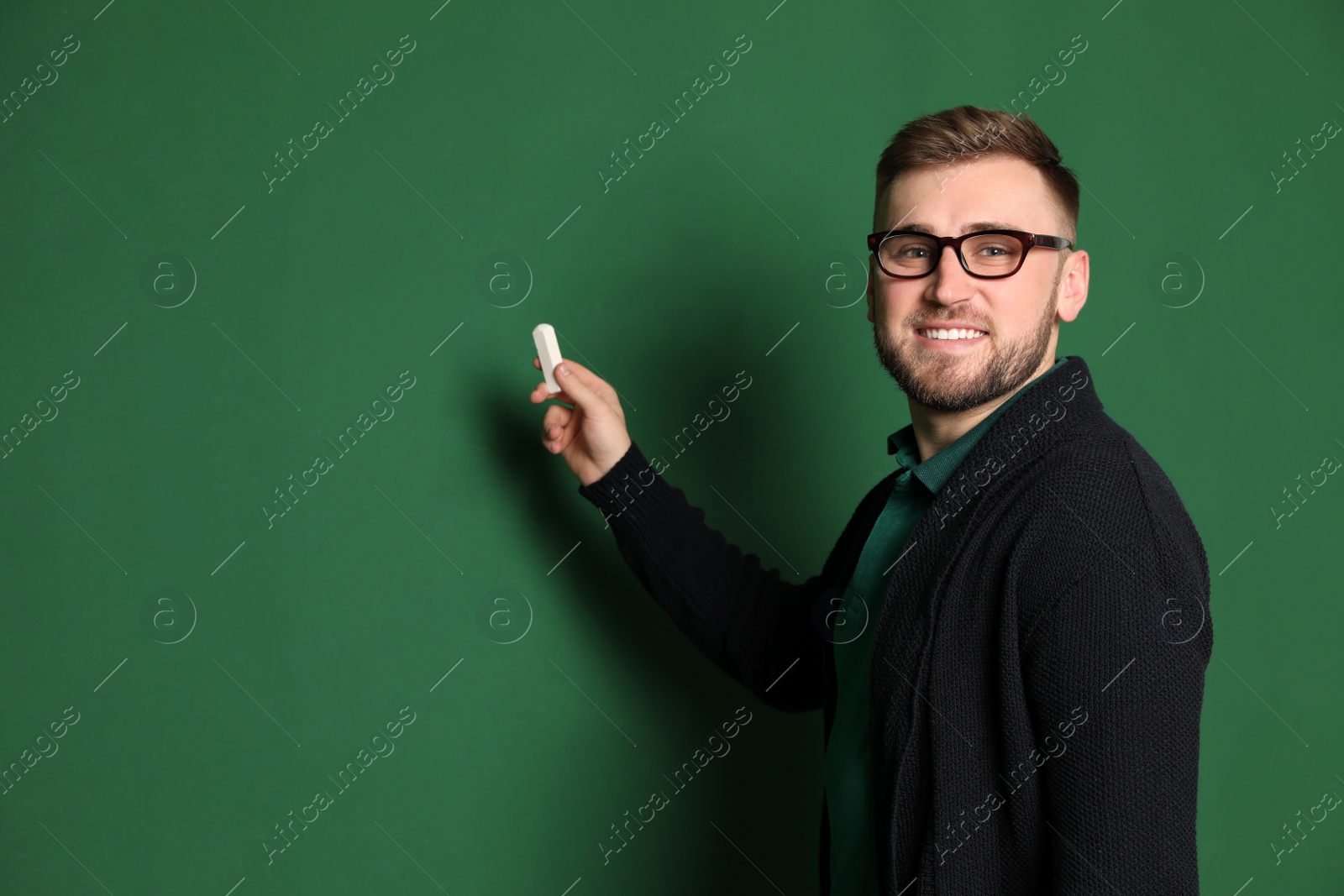 Photo of Portrait of young teacher with chalk on green background. Space for text