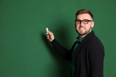 Portrait of young teacher with chalk on green background. Space for text