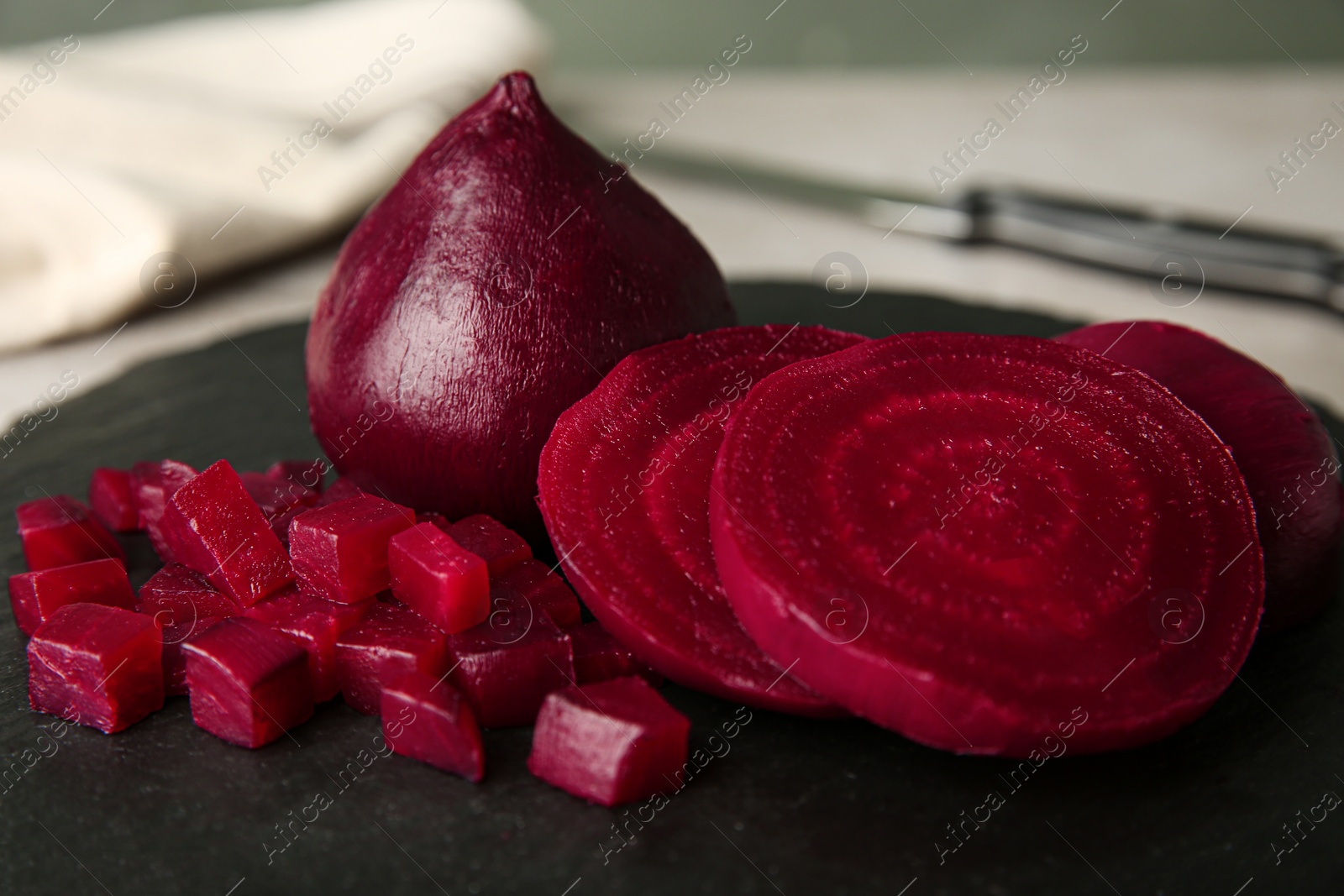 Photo of Slate plate with cut boiled beets on table, closeup