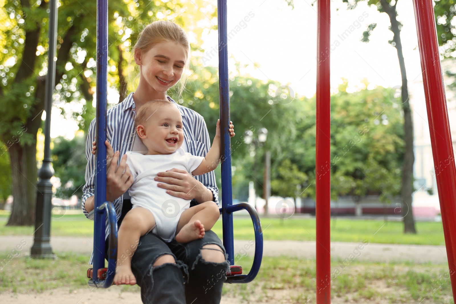 Photo of Teen nanny with cute little baby on swing outdoors. Space for text