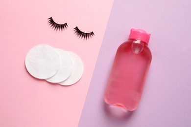 Photo of False eyelashes, cotton pads and makeup remover on color background, flat lay