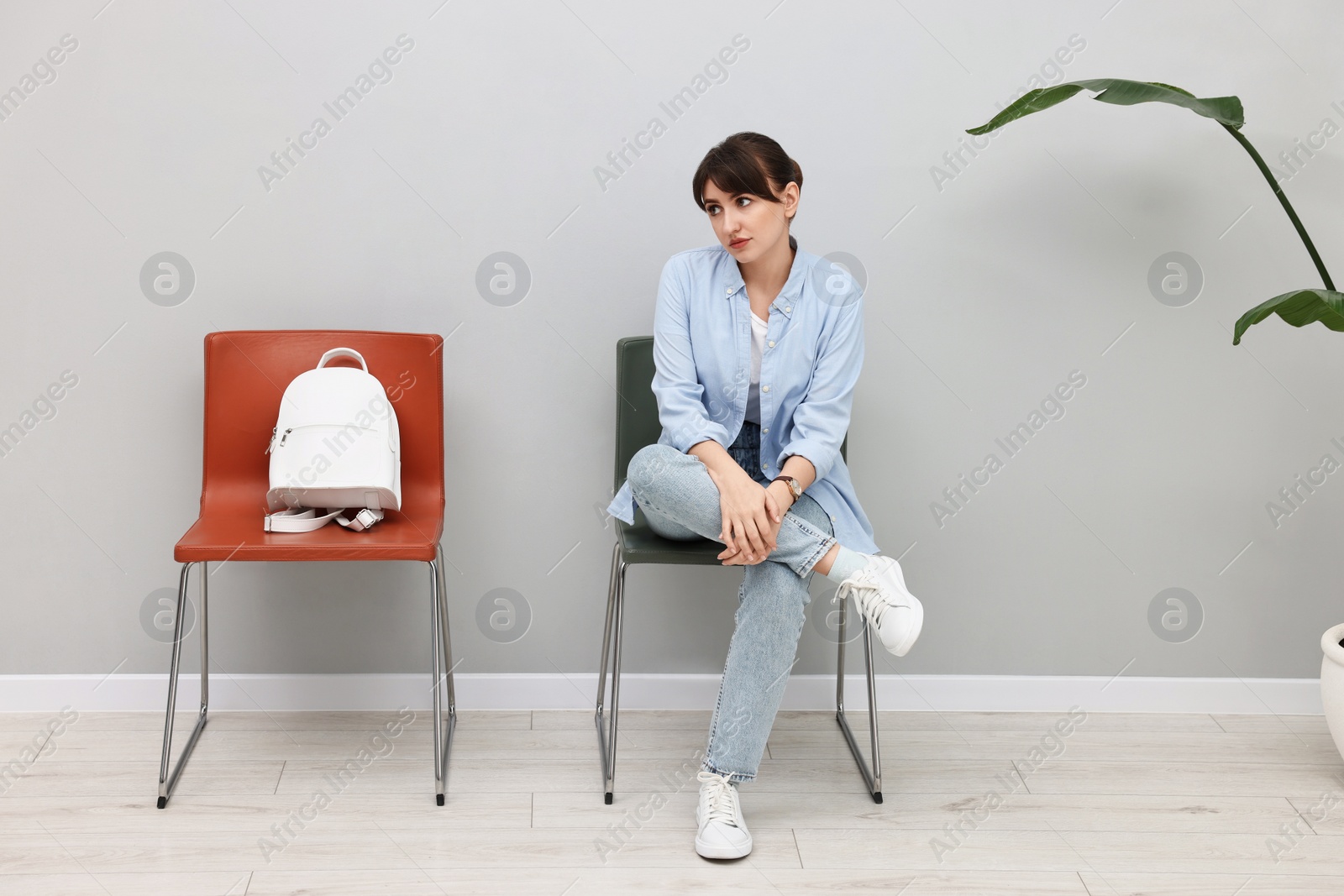 Photo of Woman sitting on chair and waiting for appointment indoors