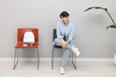 Woman sitting on chair and waiting for appointment indoors