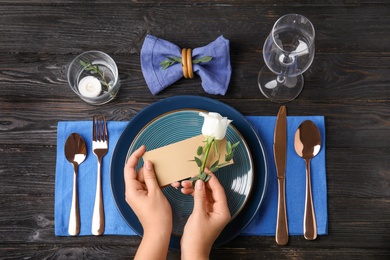 Woman setting table for festive dinner, top view
