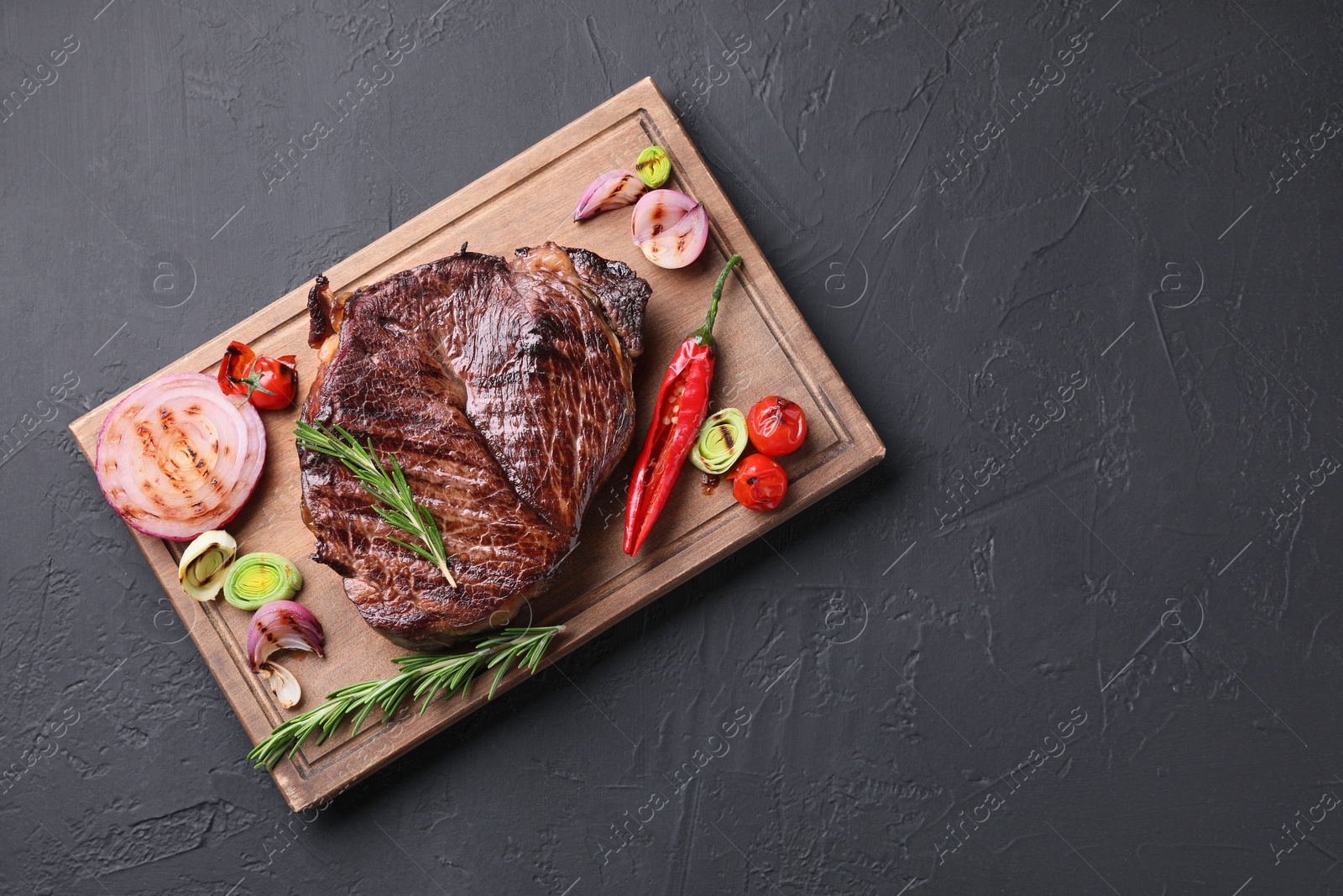 Photo of Delicious fried beef meat served with vegetables on grey textured table, top view. Space for text