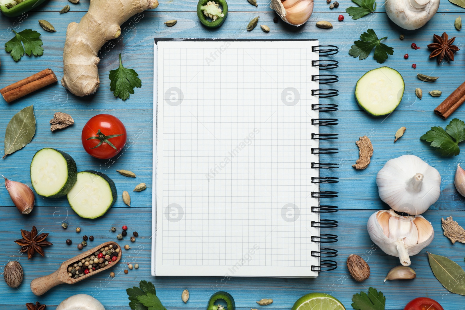 Photo of Open recipe book and different ingredients on light blue wooden table, flat lay. Space for text