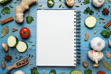 Photo of Open recipe book and different ingredients on light blue wooden table, flat lay. Space for text