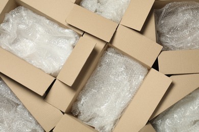 Photo of Many open cardboard boxes with bubble wrap as background, top view