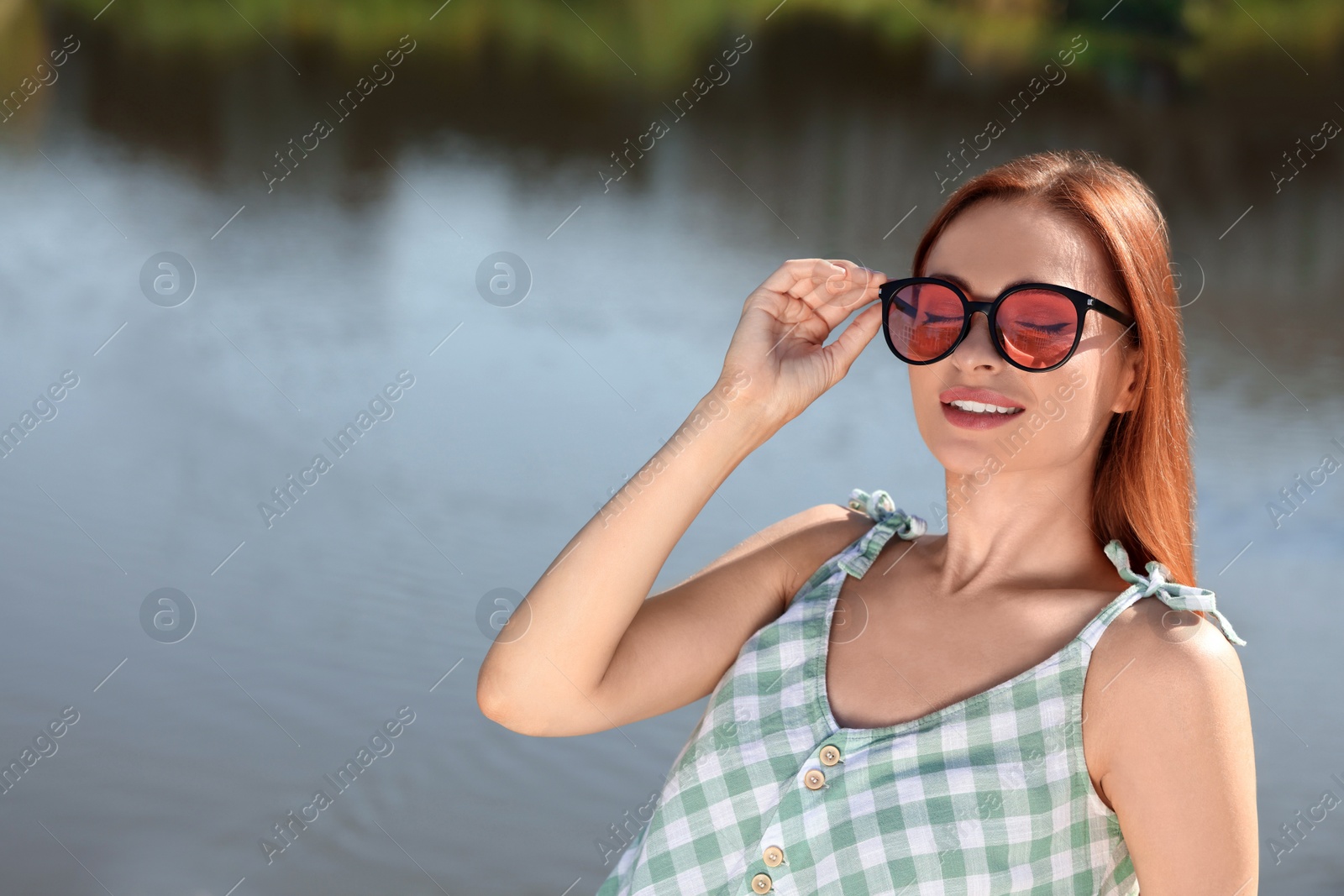 Photo of Beautiful woman in sunglasses near river, space for text