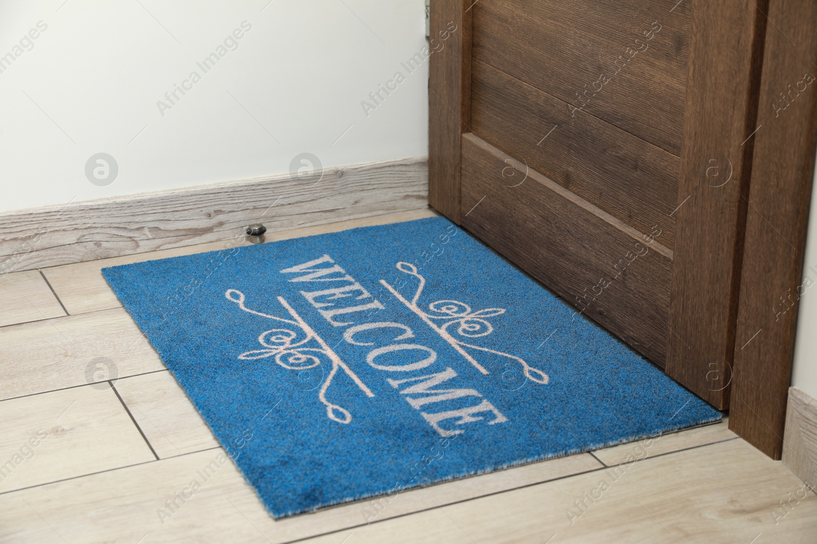 Photo of Beautiful blue doormat with word Welcome on floor near entrance