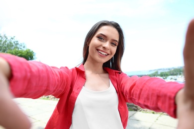 Photo of Happy young woman taking selfie on riverside