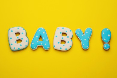 Photo of Word BABY made of tasty cookies on yellow background, flat lay