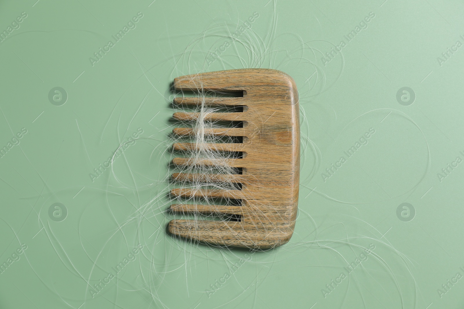 Photo of Comb with lost hair on green background, top view