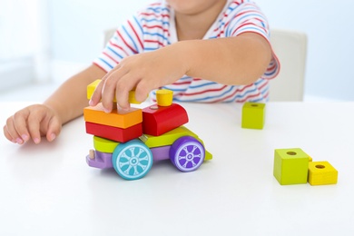 Little boy playing with toy at white table, closeup