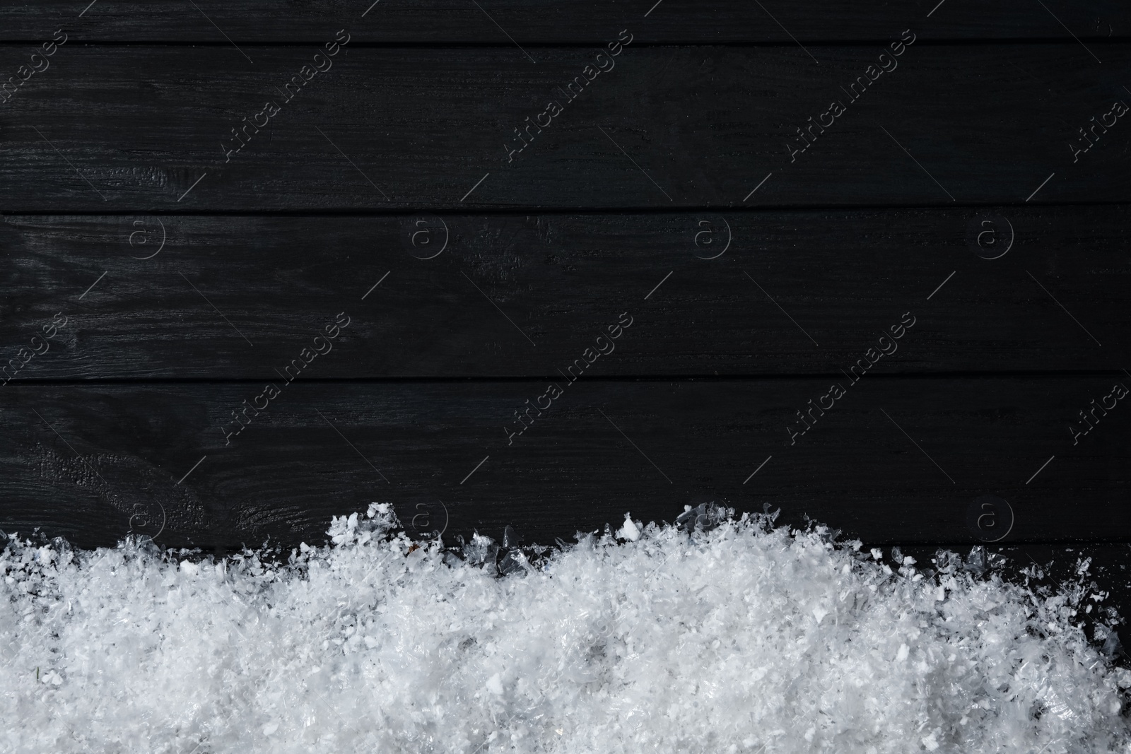 Photo of Snow and space for text on black wooden background, top view. Christmas time