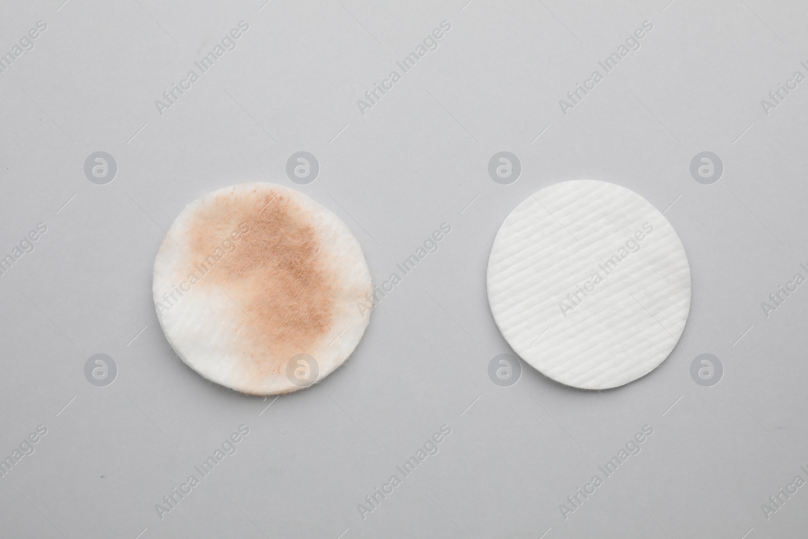 Photo of Clean and dirty cotton pads after removing makeup on light grey background, flat lay