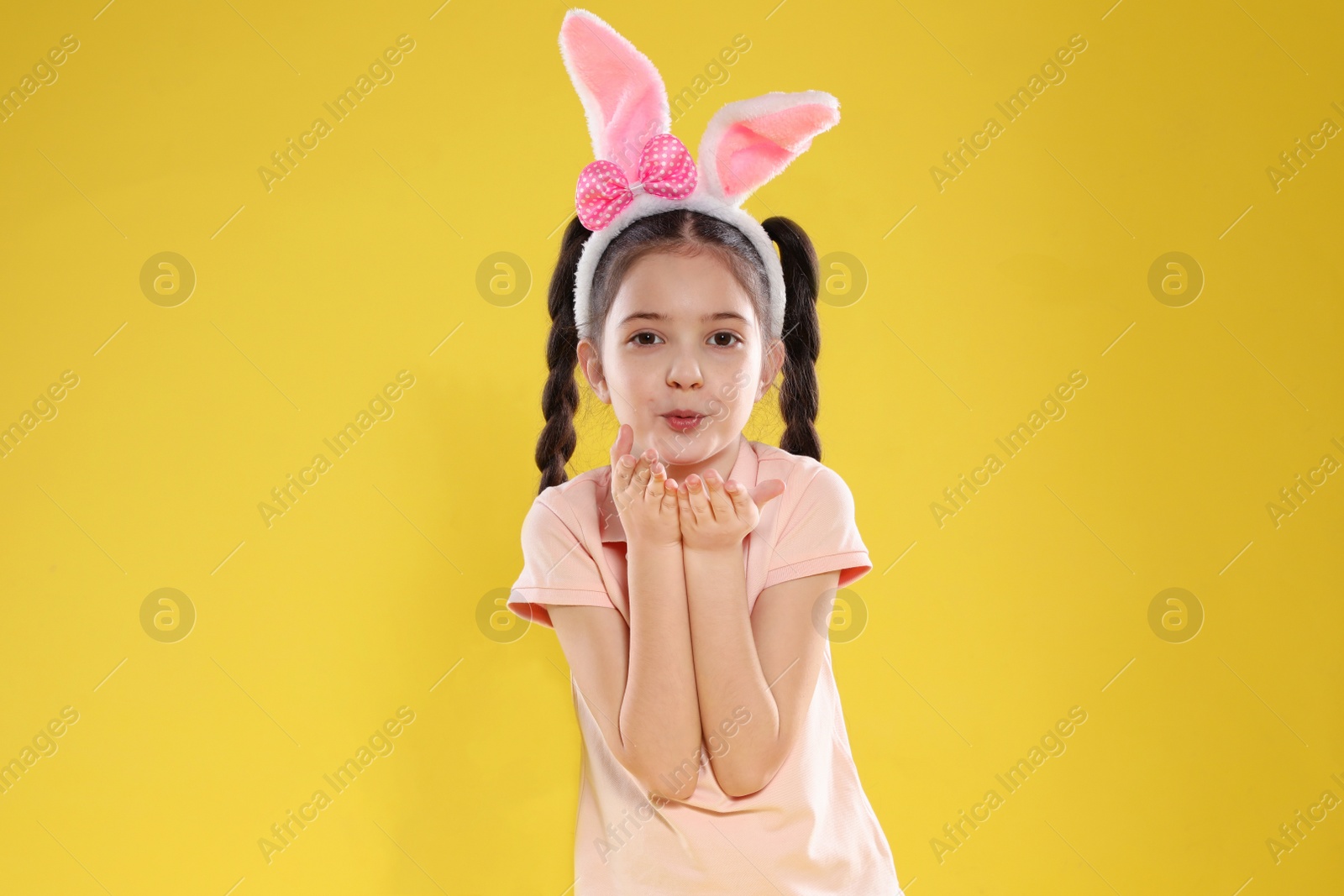 Photo of Portrait of little girl in Easter bunny ears headband on color background