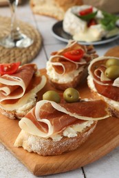 Photo of Tasty sandwiches with cured ham, tomatoes and olives on table, closeup