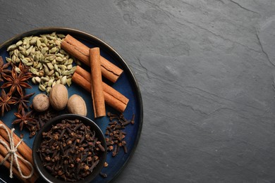 Dishware with different spices and nuts on gray table, top view. Space for text