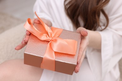 Photo of Woman holding gift box in room, closeup