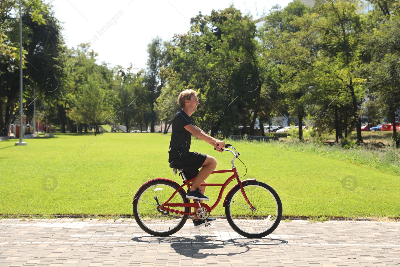 Photo of Attractive man riding bike outdoors on sunny day