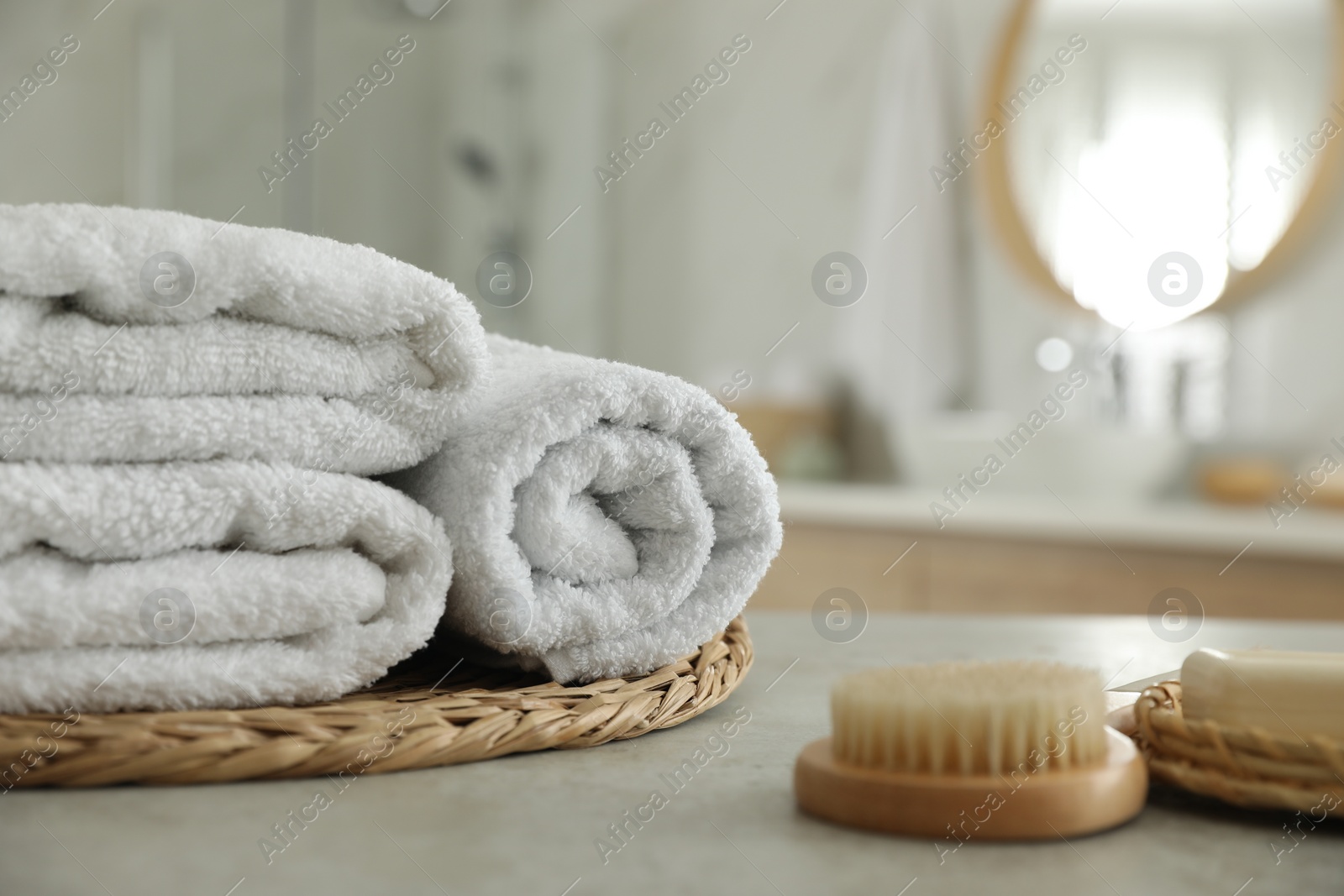 Photo of Wicker tray with clean towels on table in bathroom