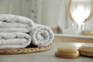 Photo of Wicker tray with clean towels on table in bathroom