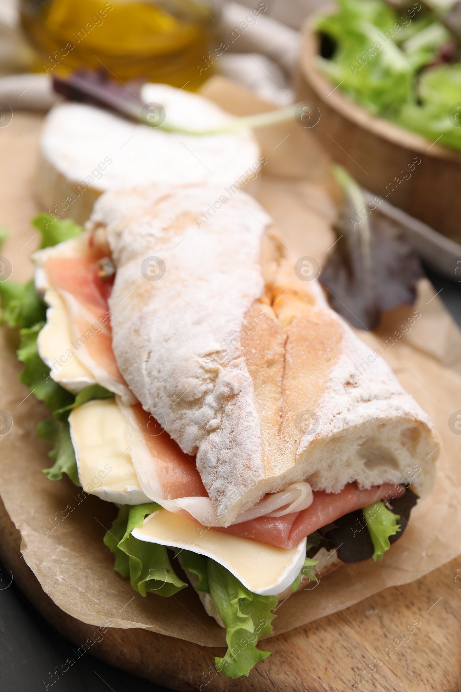Photo of Tasty sandwich with brie cheese and prosciutto on table, closeup