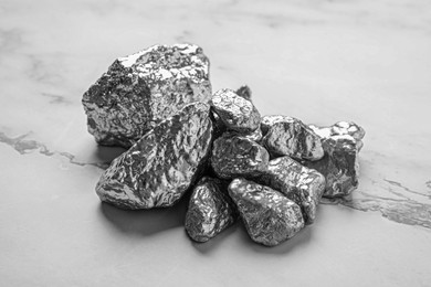 Photo of Pile of silver nuggets on white marble table, closeup