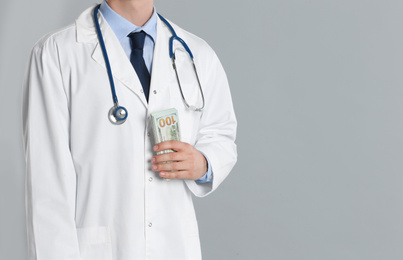 Doctor with bribe on grey background, closeup. Corruption in medicine