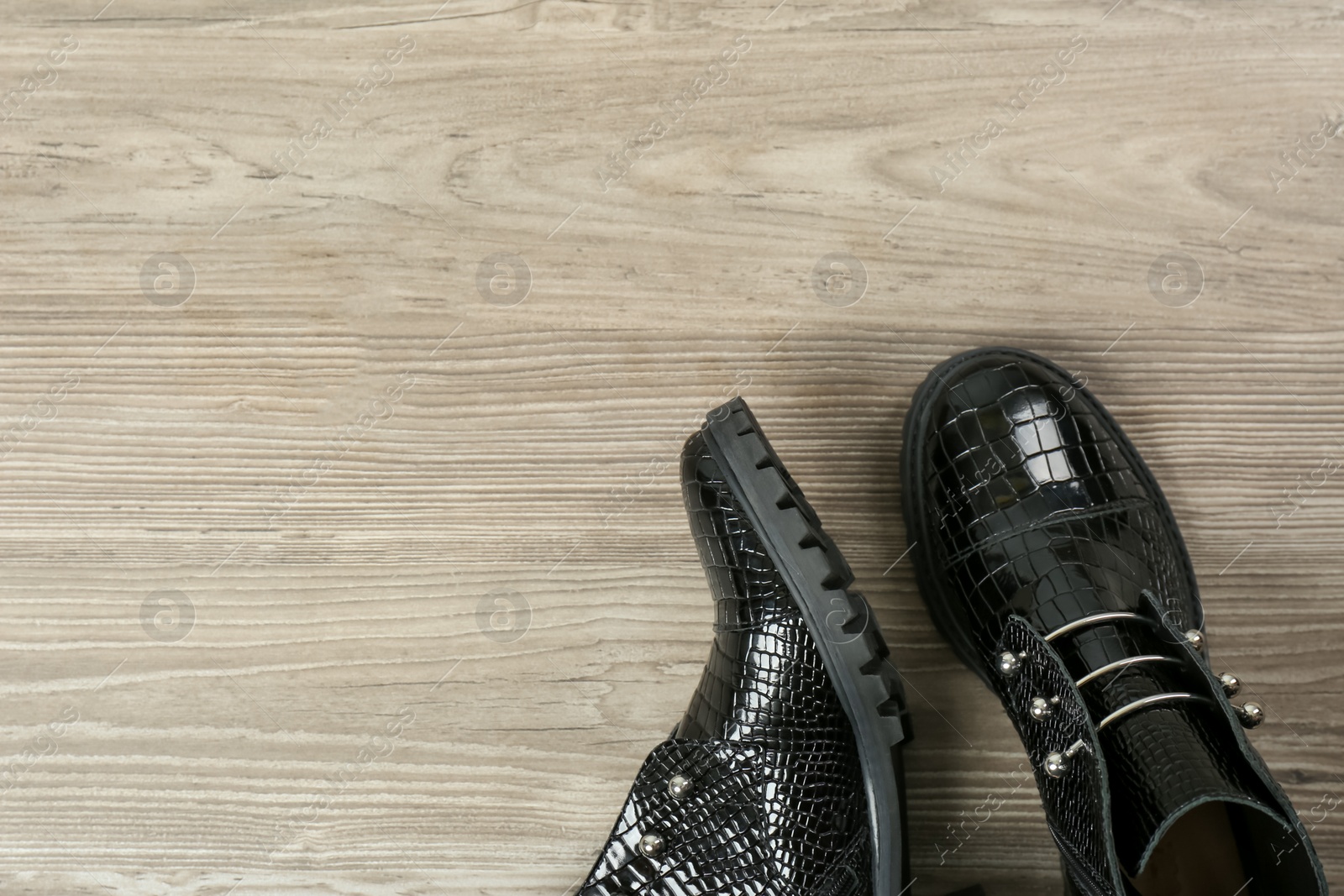 Photo of Pair of stylish ankle boots on wooden background, top view. Space for text