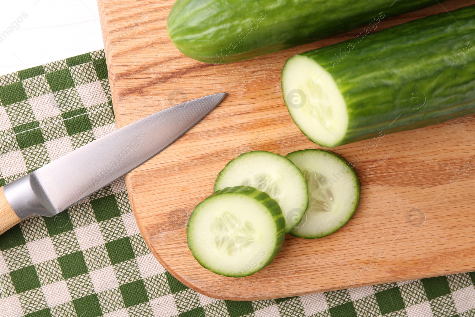 Photo of Cucumbers, knife and cutting board on table, closeup