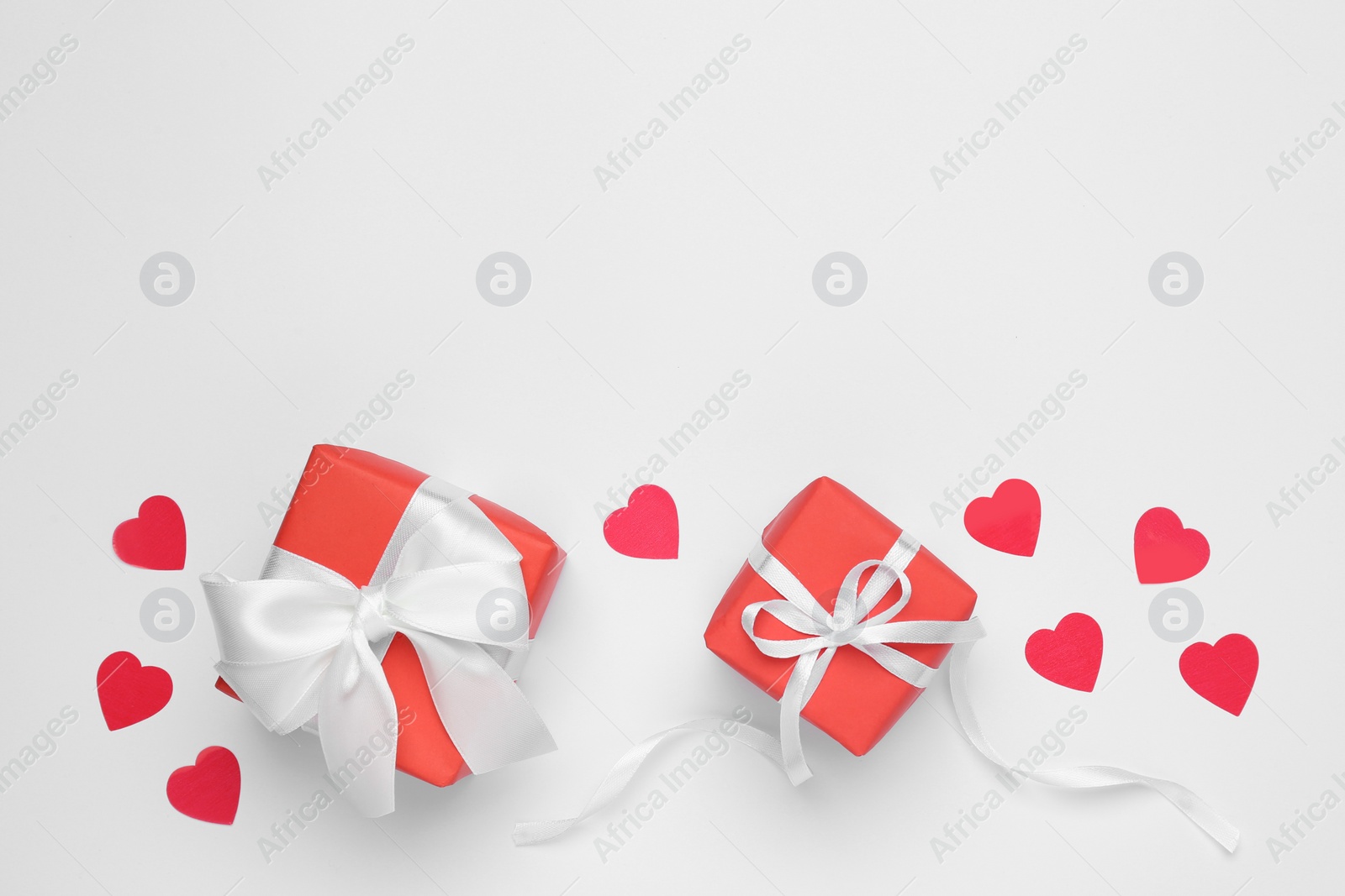 Photo of Gift boxes with decorative red hearts on white background, top view