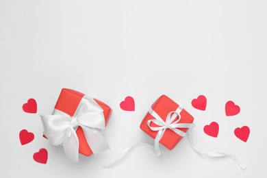 Gift boxes with decorative red hearts on white background, top view