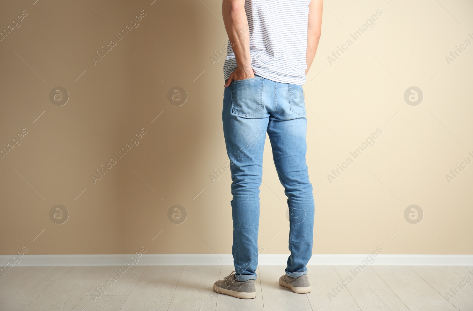 Photo of Young man in stylish jeans near light wall
