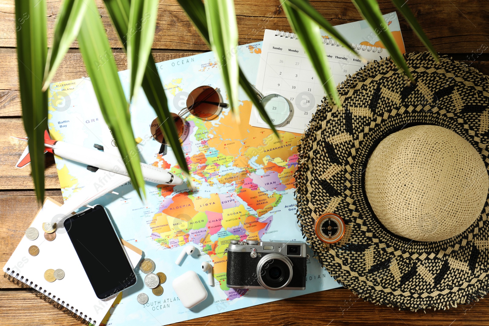 Photo of World map and items on wooden background, flat lay. Travel during summer vacation