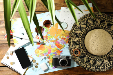 World map and items on wooden background, flat lay. Travel during summer vacation